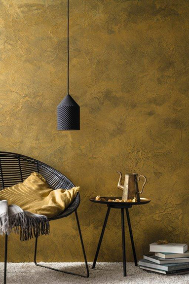 Schwarzer Korbsessel mit Hängelampe, smokey gold gestrichene Designwand
